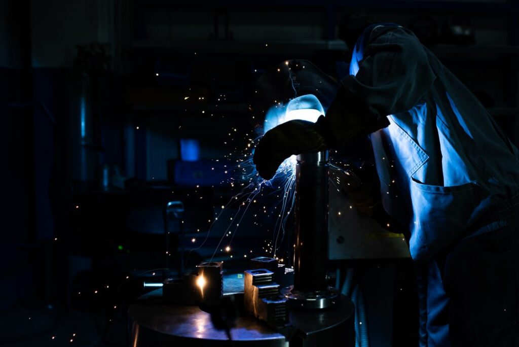 Varilec izvaja varjenje kovinskih delov z zaščitno masko.