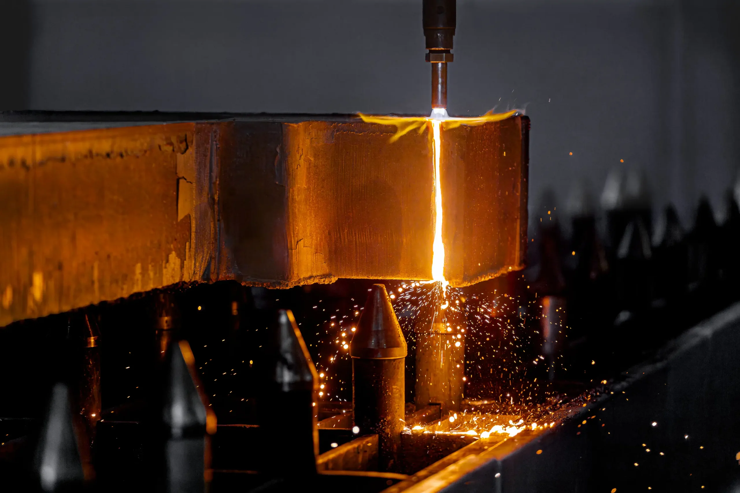 Plamenski rezalnik reže kovinsko ploščo v industrijskem obratu