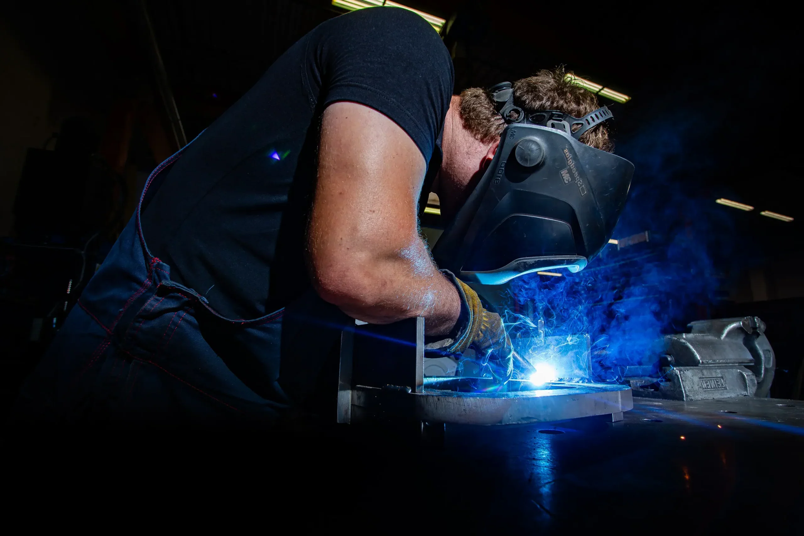 Industrijsko varjenje kovinskih konstrukcij z zaščitno masko.