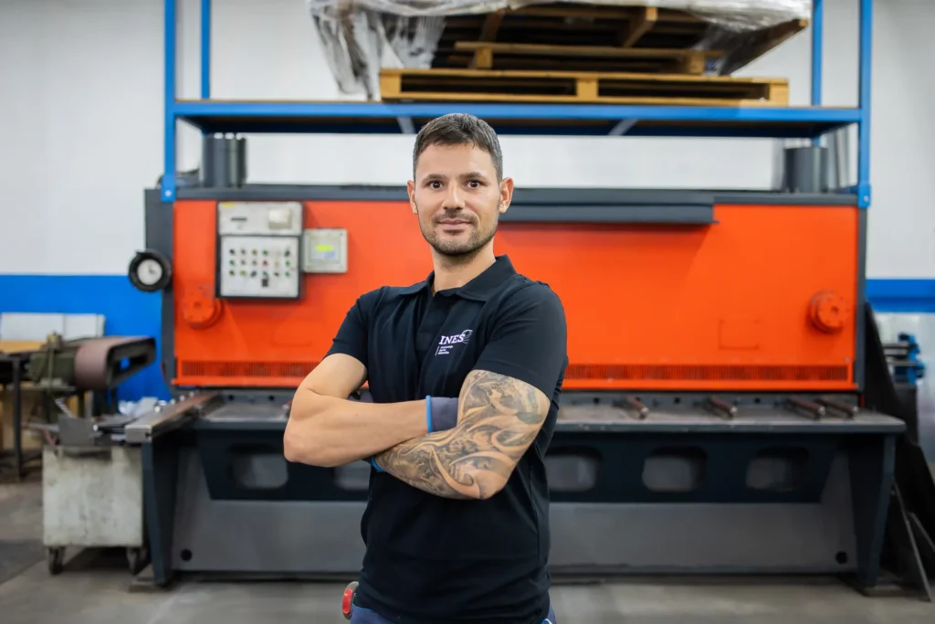 delavec stoji pred strojem za razrez pločevine s hidravličnimi škarjami