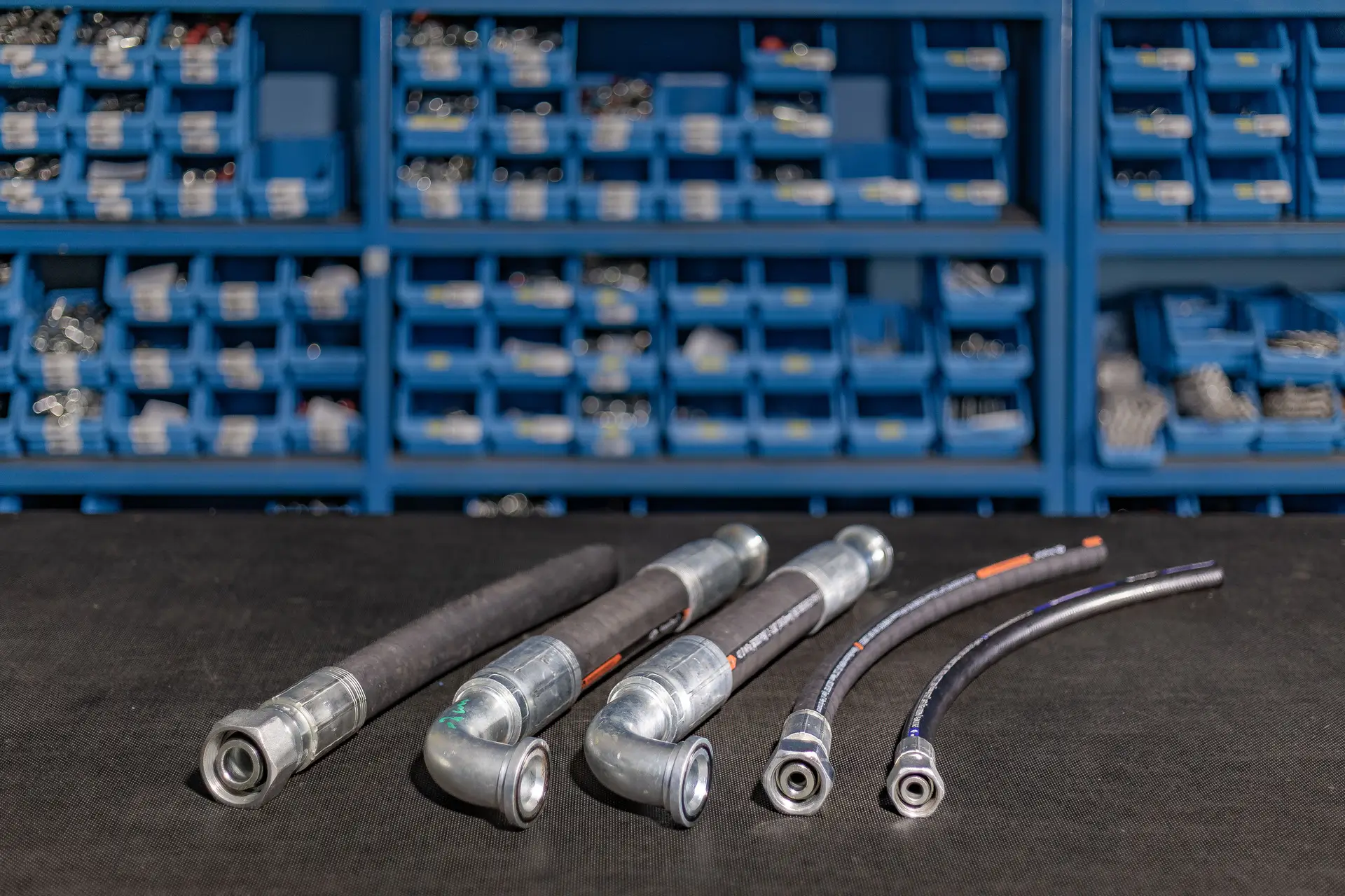 Hidravlične cevi različnih premerov in oblik z nameščenimi priključki na delovni površini.