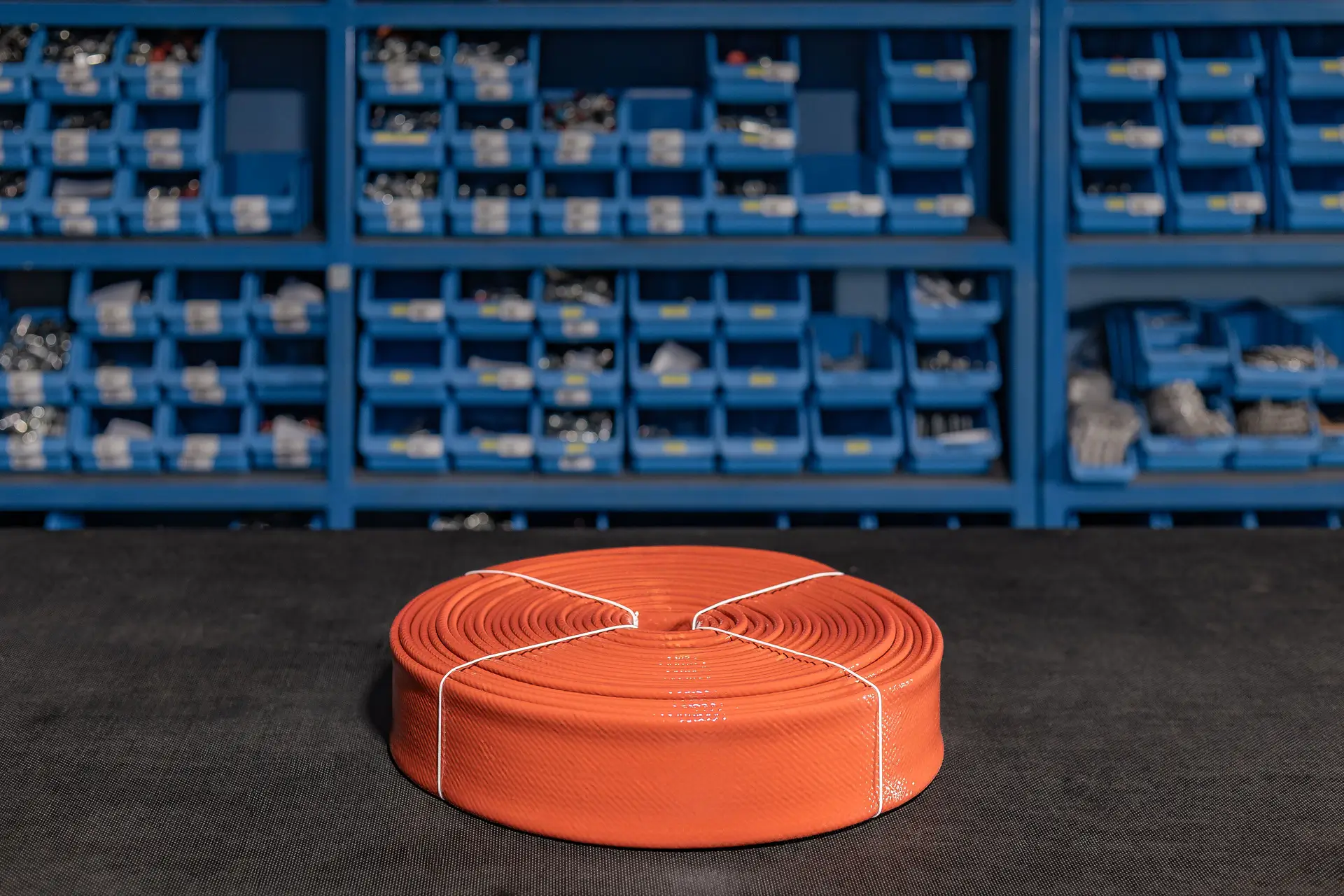 Industrijska cev v oranžni barvi, zvita v kolut in pripravljena za uporabo v hidravličnih sistemih.