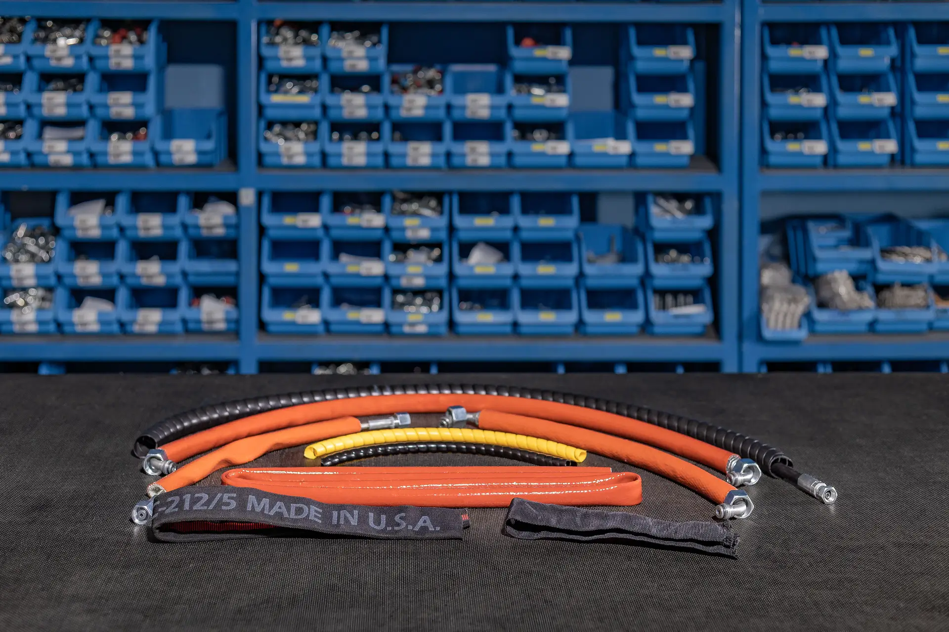 Hidravlične cevi različnih dolžin, barv in zaščitnih ovojev razporejene na delovni mizi.