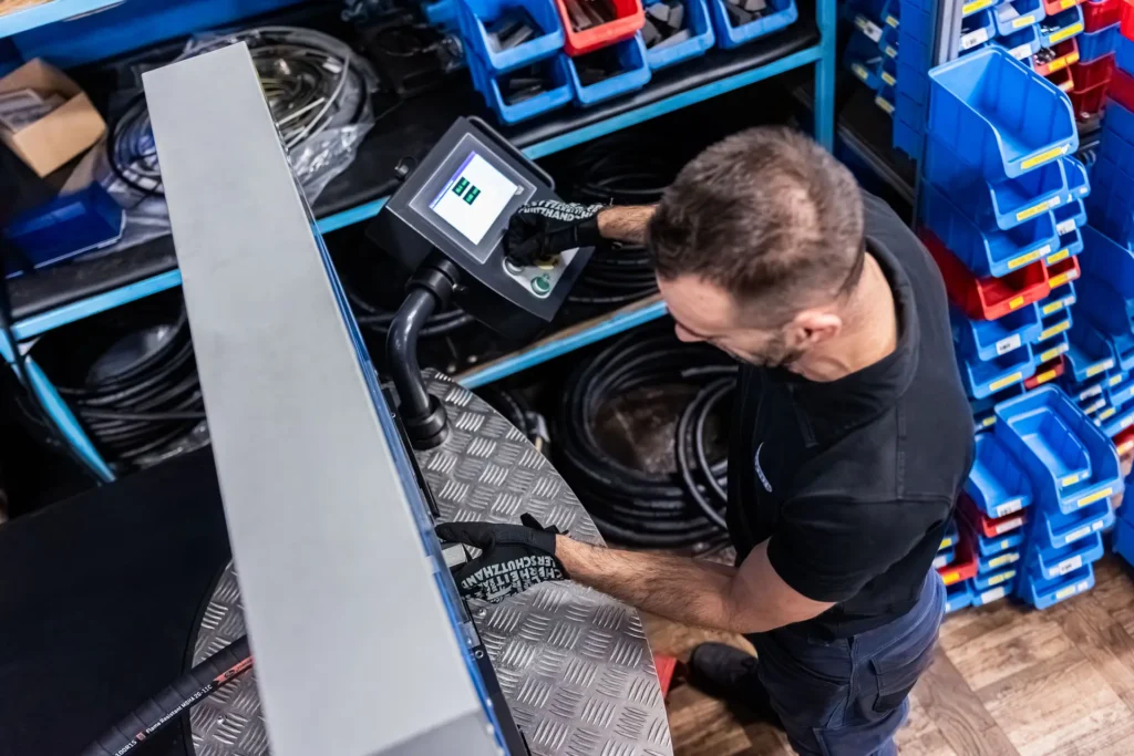 Delavec upravlja napravo za stiskanje hidravličnih cevi s pomočjo digitalnega zaslona.